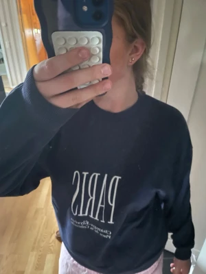 Mörkblå sweatshirt  - Mörkblå sweatshirt från Gina Tricot i storlek S med vit text 'PARIS' och tryck framtill. Tröjan har rund hals, långa ärmar och ribbade muddar vid ärmslut och nederkant. Perfekt för en chill och snygg look. Säljs då den hängt i garderoben ett bra tag och inte används.
