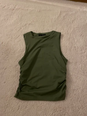 Olivgrön topp - Snygg olivgrön linnetopp från Shein med rund hals och rynkade sidor med snörningsdetalj. Stretchigt material som sitter bekvämt och figurnära. Använd ett fåtal gånger.