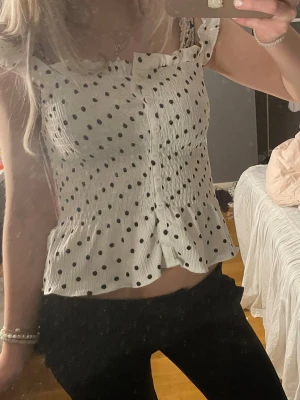 Vit prickig linnetopp med knappar - säljer min supersöta linnetopp med svarta prickar och en liten volang nertill. Endast andvänd en gång, säljer då den tyvärr inte kommer till andvändning❣️❣️skriv om du har några frågor!