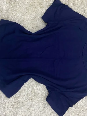 Mörkblå basic t-shirt  - En enkel mörkblå t-shirt med rund halsringning och korta ärmar. Perfekt till jeans eller shorts för en clean och avslappnad look. Klassisk passform utan tryck eller mönster. Priset kan diskuteras 