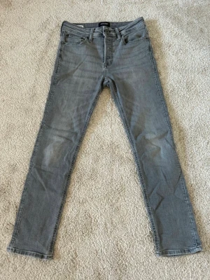 Gråa skinny jeans från Jack and Jones - Säljer ett par gråa skinny jeans från Jack and Jones Jeansen har klassisk femficksdesign, bälteshällor och dragkedjegylf. Materialet är mjukt jeans-tyg och passformen är tight hela vägen ner. Perfekta till en avslappnad streetstil.