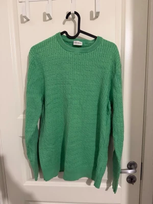 Grön stickad tröja John Henric L - Snygg grön stickad tröja från John Henric i storlek L. Tröjan har ett klassiskt kabelstickat mönster, rund halsringning och långa ärmar. Perfekt för dig som vill ha en stilren och fräsch look till både vår och höst.