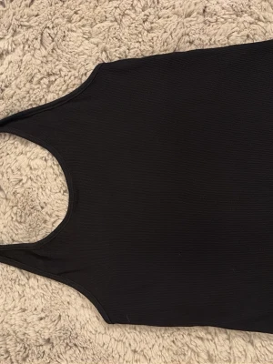 Svart ribbad linnetopp Gina Tricot - Säljer en svart ribbad linnetopp från Gina Tricot i storlek 158/164. Toppen har en enkel och clean design med hög ringning och ärmlöst snitt. Perfekt att matcha med jeans eller kjol för en chill look.