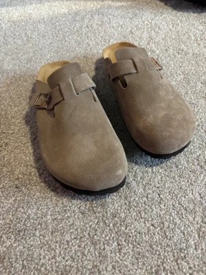 Birkenstock Boston mocka - Birkenstock Boston sandaler i taupefärgad mocka med rund tå och justerbart spänne i metall. SOFT Modell. Så dom är mjukare och skönare. 