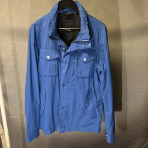 Field jacka j lindeberg blå L - Tvärfet field jacka från j lindeberg! Size L! Kan även funka på en M om du är mellan M o L! Skick 8,5/10 begagnad men väldigt bra skick! Det är den klassiska poppulära modellen i en lite unikare färg som är sjukt snygg o fräsch! Hör av dig vid frågor🤩