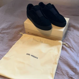 Svarta sneakers från Axel Arigato - Snygga svarta sneakers från Axel Arigato i storlek 45 och även mocka med minimalistisk design. Perfekt för dig som gillar stilrena och moderna skor. Har tyvärr bara påsen kvar då vi slängde lådan då den tog plats. Köpta på NK i Göteborg 