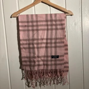 Burberry scarf - Burberry scarf i använt skick. Scarfen har 2 mindre hål oså lite små hål som knappt syns men den är i ganska dåligt skick därav priset på 99 kr! Scarfen tillkommer gratis vid köp av ett par jeans eller skor