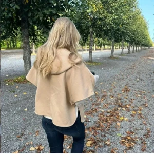 Beige kappa med huva och dragkedja - Snygg beige kappa med huva och dragkedja framtill. Jackan har en loose passform och är tillverkad i ett mjukt ullmaterial. Perfekt för dig som gillar stilrena och chill plagg med lite extra volym över axlarna.