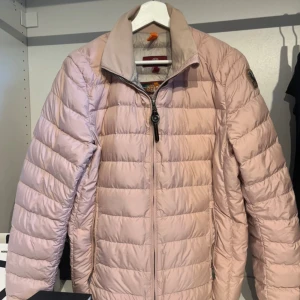 Ljusrosa dunjacka från Parajumpers - Lätt och smidig ljusrosa dunjacka från Parajumpers med quiltad design och dragkedja framtill. Jackan har hög krage och diskret logga på ärmen. Perfekt för dig som vill ha en snygg och funktionell jacka med stilren look. Nypris cirka 3500 kr. Pris går att diskutera.