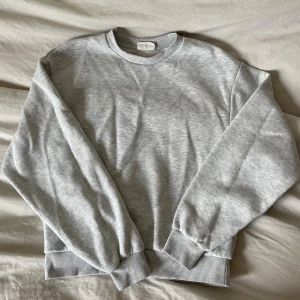 Ljusgrå sweatshirt  - En stilren ljusgrå sweatshirt med rund halsringning och ribbade muddar vid ärmslut och nederkant. Perfekt för en chill och avslappnad look. Tillverkad i mjuk bomullsmix och har en klassisk passform med långa ärmar.