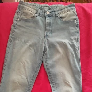 Ljusblå jeans med dekorerade bakfickor - Snygga ljusblå jeans med femficksdesign och dekorativa sömmar samt nitar på bakfickorna. Jeansen har normal passform och stängs med knapp och dragkedja. Materialet är mjukt denim och färgen är lätt tvättad. 