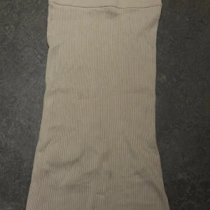 Beige ribbad långkjol med slits - Säljer en beige ribbad långkjol med tight passform. Kjolen har en snygg slits baktill som ger extra edge och är gjord i ett stretchigt, stickat material. Storlek M. Säljer för 50kr