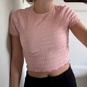 Ljusrosa croppad topp i smock - Säljer en ljusrosa croppad topp med smockad struktur och korta ärmar. 