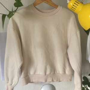 Beige sweatshirt från Gina Tricot - En basic beige sweatshirt från Gina Tricot, basically basics-kollektionen. Tröjan har rund hals, ribbade muddar vid ärmslut och nederkant samt en avslappnad passform. Perfekt för en chill och enkel stil.