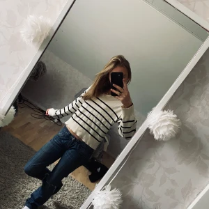 Randig vit och svart stickad tröja - Säljer en snygg vit/beige stickad tröja med svarta horisontella ränder. Tröjan har en croppad passform och långa ärmar🌟🩷