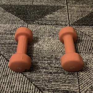 2 kg hantlar (par) – Rosa  - Säljer ett par orange hantlar på 2 kg vardera. Perfekta för hemmaträning eller gruppträning. Ena hanteln har en synlig skada i gummit, men båda är fullt användbara. Greppvänlig yta och kompakt storlek. Säljes i befintligt skick.