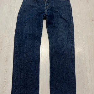 mörkblå jeans - Mörkblå Levi's 555 jeans med klassisk femficksdesign och raka ben. Jeansen har snygga kontrastsömmar och läderpatch bak i midjan. Tillverkade i slitstarkt denimtyg som ger en tidlös look. Nypris 1200