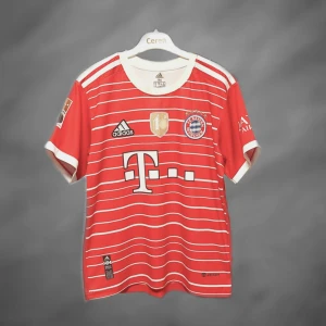Bayern München Kimmich matchtröja Adidas - Röd och vit Bayern München fotbollströja från Adidas med Kimmich #6 på ryggen. Tröjan har korta ärmar, tunnt funktionsmaterial och vita horisontella ränder. Broderat klubbmärke, sponsorlogga och guldmärke på bröstet. Perfekt för fans av FC Bayern.