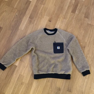 Beige fleece-tröja Carhartt S - Säljer en beige fleece-tröja från Carhartt i storlek S. Tröjan har svarta muddar, svart bröstficka med dragkedja och Carhartt-logga. Perfekt för kyliga dagar med sin mjuka och mysiga känsla. En väldigt skön tröja som passar till allt och håller även värme mot vintern. Säljer då den ej passar mig längre. Storlek S i vuxen storlek 
