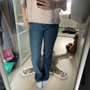 Blå raka jeans  - Klassiska blå jeans med rak passform och normal midja. Jeansen har fem fickor, enkel design och är tillverkade i slitstarkt denim. Perfekta för en avslappnad och stilren look.