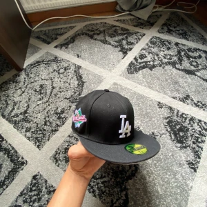 Svart LA Dodgers keps New Era 59FIFTY - Storlek 7 1/8 (58,6 cm) vill sälja därför att den är för liten på mig. Den är i nyskick dock är det inbuklad vänster om LA loggan. Går att fixas enkelt. Prutning vid snabbaffär.