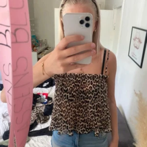 Leopardmönstrad ärmlös linnetopp - Säljer en snygg ärmlös linnetopp med leopardmönster. Toppen har smala axelband och en luftig, lätt rynkad passform som ger en cool och avslappnad vibe. Perfekt att matcha med jeans eller kjol för en trendig look.