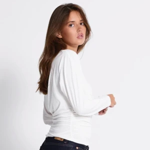 Vit offshoulder topp med rynkade sidor - Säljer en vit långärmad topp från 157 med offshoulder-design och rynkade sidor. Toppen är i mjuk bomull och har en figurnära passform som framhäver midjan. Perfekt för dig som gillar en stilren och trendig look.