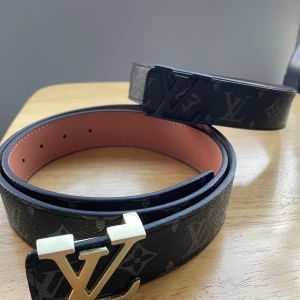 H&M svart monogram bälte - Säljer 2 H&M bälte i svart med klassiskt monogrammönster och H&M-spänne i guld eller svart. Bältet är gjort i skinn med en slät brun insida och har exklusiv känsla. Perfekt accessoar för att lyfta din outfit.