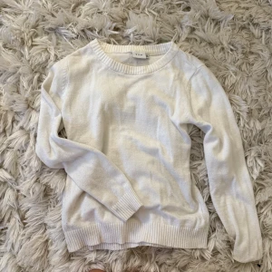 Vit stickad tröja från Vila - Klassisk vit stickad tröja från Vila med rund halsringning och ribbade muddar vid ärmslut och nederkant. Perfekt basplagg med lång ärm och mjuk känsla, passar till allt och är enkel att styla.