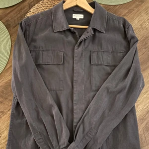 Mörkgrå overshirt från These Glory Days - Säljer min overshirt för har ingen användning av den längre, den är mycket bra skick och du får me två nya knappar ifall någon skulle gå sönder. Pris går att diskuteras 