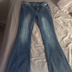 Blå bootcut jeans med broderade fickor - Snygga blå bootcut jeans med ljusa slitningar och broderade bakfickor med nitar. Klassisk femficksmodell och dragkedja fram. Perfekta för dig som gillar en retro vibe och vill sticka ut lite extra. Bra skick, oanvänd , ställ frågor om de behövs 💕