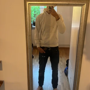 Vit hoodie från Jack & Jones - Vit hoodie från Jack & Jones med klassisk känguruficka och snörning i huvan. Tröjan har ribbade muddar och är tillverkad i mjuk bomull. Perfekt för en clean och avslappnad stil.