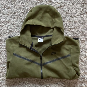 Olivgrön Nike hoodie med dragkedja - Nike hoodie i olivgrönt med hel dragkedja och svarta detaljer. Tröjan är storlek M och är i Jätte bra skick