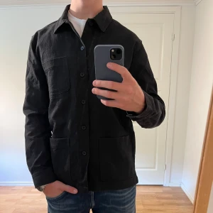 Svart Overshirt med knappar  - Säljer denna sjukt snygga Overshirten från Nuew⭐️ Färgen är svart och storleken är M✅ Den har inga defekter och skicket är utomordentligt🙌🤝 Sjukt najs passform och passar perfekt till hösten🍁🙌 Tveka inte på att höra av er dig vid minsta fråga eller fundering😊