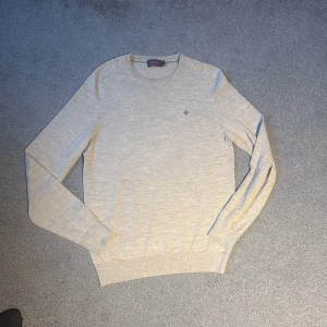 Beige merinoullströja från Morris - Säljer en stilren beige tröja från Morris i 100% merinoull. Tröjan har rund halsringning, lång ärm och en liten broderad logga på bröstet. Perfekt för lager-på-lager och passar till många olika outfits. Nypris 1599kr!