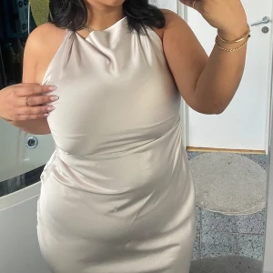 Krämfärgad satinklänning - Midiklänning. Endast använd en gång. Superfin i verkligheten. Köpt från Zara för cirka 500 kronor. Storlek L. Köparen står för frakten.