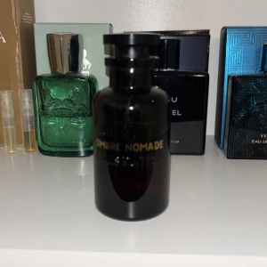 Ombre Nomade parfym Louis Vuitton - Lyxig parfymflaska från Louis Vuitton, Ombre Nomade. Flaskan är mörkbrun med guldfärgad text och har en elegant, rund form. Perfekt för dig som gillar exklusiva dofter och snygg design på parfymhyllan.