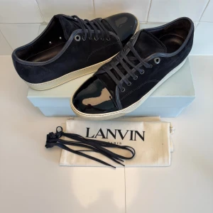 Lanvin skor  - Snygga mörk blå sneakers från Lanvin med ovandel i mocka och glansig lackad tå. Allt og tillkommer vid köp!!! Uk 8 passar 42-43. Bara att höra av sig till oss vid minsta funderingar😁