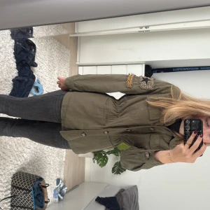 Olivgrön ”militärjacka” med patch - Från chelsea, har använt den 2 gånger. Köpte för 400. Säljer en olivgrön militär jacka med  broderade patchar på ärmen, bland annat en stjärna. Man kan knyta den om man vill ha den lite mer tajt runt midjan. Jackan har fyra fickor framtill, knappar hela vägen och klassisk krage. Storlek S