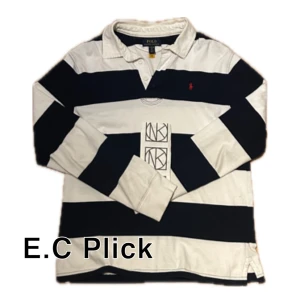 Randig pikétröja från Polo Ralph Lauren - Snygg långärmad pikétröja från Polo Ralph Lauren med breda marinblå och vita ränder. Klassisk krage, knappar vid halsen och ikonisk röd logga broderad på bröstet. Tillverkad i mjuk bomull, perfekt för en sportig och stilren look. Finns kvitto storlek L i barn så storlek S ungefär i herr