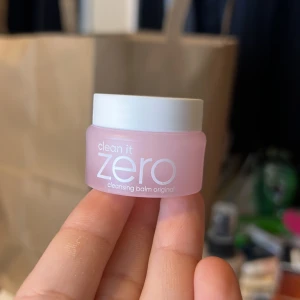 Clean It Zero Cleansing Balm original Mini - Supersöt miniburkar av Clean It Zero Cleansing Balm från Banila Co. Burken är ljusrosa med vitt lock och innehåller en fast, vit balm som smälter bort smink. Perfekt att ha med i väskan för smidigt sminkborttagning. K-beauty klassiker! Gjord i Korea. Helt oanvänd.