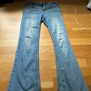 Blå bootcut jeans med utsvängda ben - Snygga blå jeans med bootcut och utsvängda ben. Klassisk femficksmodell med knapp och dragkedja framtill. Jeansen har en ljus tvätt och är tillverkade i mjukt denimtyg som ger en avslappnad vibe.