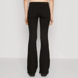 Svarta bootcut byxor - Snygga svarta byxor med bootcut passform och hög midja. Byxorna har klassisk femficksdesign och är perfekta för dig som gillar en stilren och trendig look. Materialet är stretchigt och bekvämt, vilket gör dem lätta att bära hela dagen.