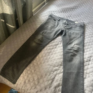 Grå jeans från Diesel - Snygga grå jeans från Diesel med klassisk femficksdesign och diskreta slitningar. Jeansen har raka ben och normal passform, med Diesel-logga på bakfickan och läderpatch i midjan. Perfekta för dig som gillar en stilren och avslappnad look. Säljer pga satt för skinny på mig .