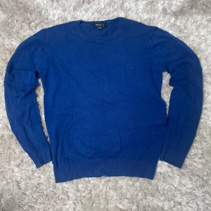 Blå bomullströja med armbågslappar - Säljer en blå långärmad tröja från H&M Basic i bomull. Tröjan har rund halsringning och svarta armbågslappar på båda ärmarna. Perfekt för dig som gillar en enkel men stilren look.