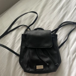 Svart liten ryggsäck - Liten svart ryggsäck från Victoria’s secret. Knappt använd och jättesöt modell