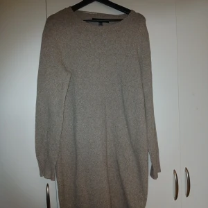 Beige stickad långklänning - Mysig beige stickad långklänning från H&M med rund hals och långa ärmar. Perfekt för dig som gillar enkel och stilren design. Materialet är mjukt och håller dig varm under kyliga dagar. Passar dig som vill ha en avslappnad och bekväm look.