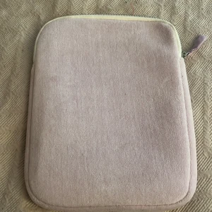 Ljusrosa datorväska med blommigt foder - Supersöt ljusrosa datorväska i mjuk sammet med dragkedja och matchande tygdetalj. Insidan har ett blommigt foder i grönt och orange som ger en extra touch. Perfekt för att bära din laptop med stil och lite extra färg på insidan.