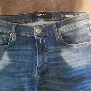 Blå jeans från Replay - Snygga blå skinny jeans från Replay med klassisk femficksdesign. Jeansen har en mellanblå tvätt med ljusare partier och sitter tight hela vägen ner. Perfekta för dig som gillar en smal siluett och stilren look. 27/32