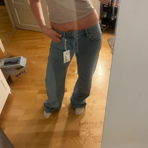 Ljusblå low waist jeans, straight fit - Säljer ett par ljusblå jeans med låg midja och raka ben. Jeansen har klassisk femficksdesign och är i en skön bomullsdenim. Perfekta för dig som gillar en avslappnad och trendig look. Storlek EU 32. NAKD JEANS färg LIGHT BLUE, prislapp kvar, säljer då de är för långa, nypris 699
